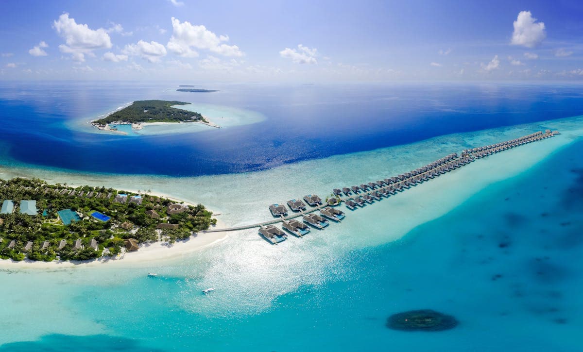 Maldives overwater bungalow on turquoise lagoon at golden sunset